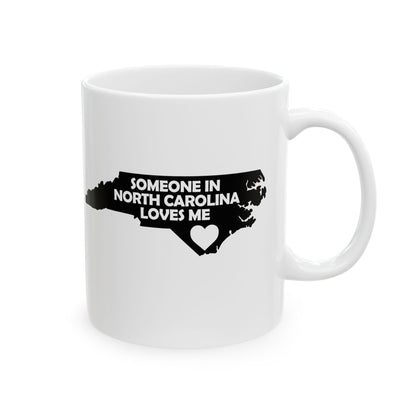 White mug with black text and map of North Carolina on a white background with text  Someone In North Carolina Loves Me
