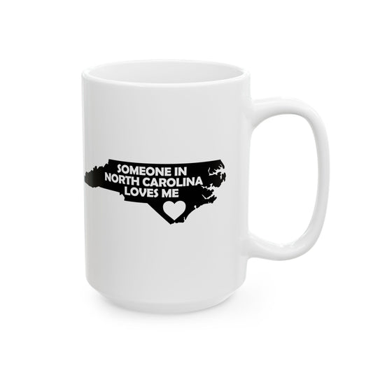 White mug with black text and a heart shape on a white background with text  Someone In North Carolina Loves Me