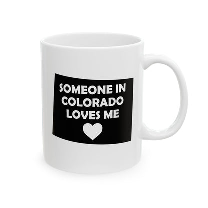 White mug with black label text 'SOMEONE IN COLORADO LOVES ME' and a heart symbol on a white background
