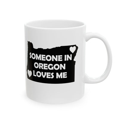 White mug with black design of Oregon map and text 'Someone in Oregon loves me' on a white background