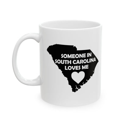 White mug with black silhouette of South Carolina and text 'Someone in South Carolina loves me' on a white background