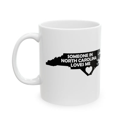 White mug with black text and map of North Carolina on a white background with text  Someone In North Carolina Loves Me