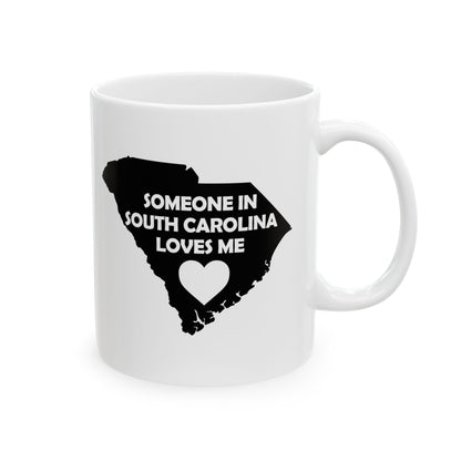White mug with black silhouette of South Carolina and text 'Someone in South Carolina loves me' on a white background