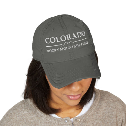 Person wearing a gray cap with 'Colorado Rocky Mountain State' text  embroidered in white thread